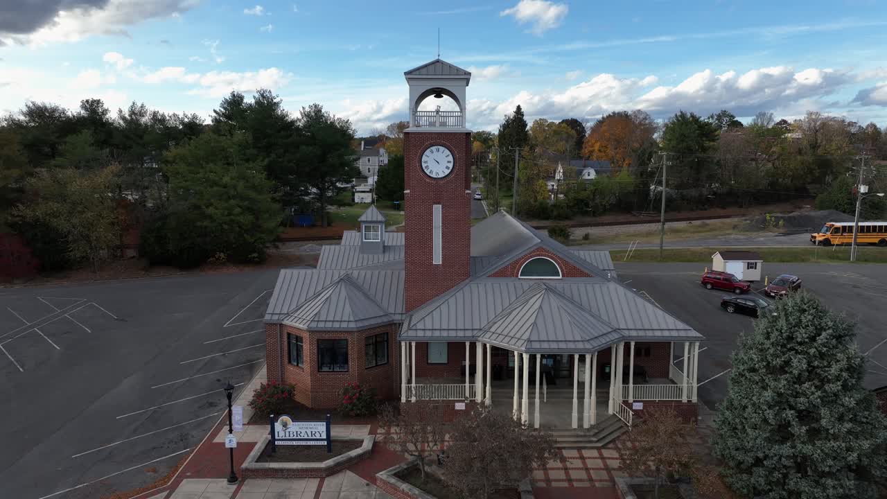 Aerial approaching shot of historic Library in american town. Clock tower and yellow school bus in background. Autumn day in american city.
