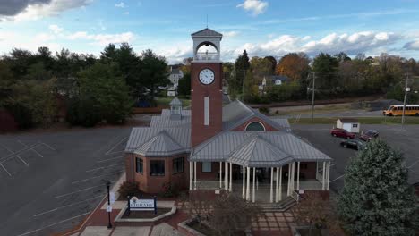 aerial approaching shot of historic library in american town. clock tower and yellow school bus in background. autumn day in american city.