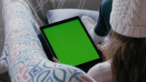woman using digital tablet computer watching green screen relaxing at home on couch enjoying online entertainment