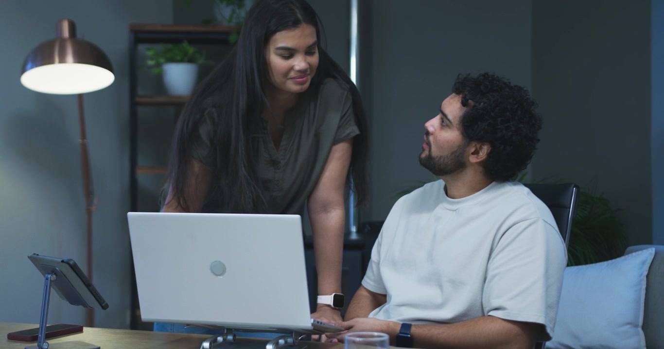 Dos colegas colaborando en un portátil en una oficina moderna