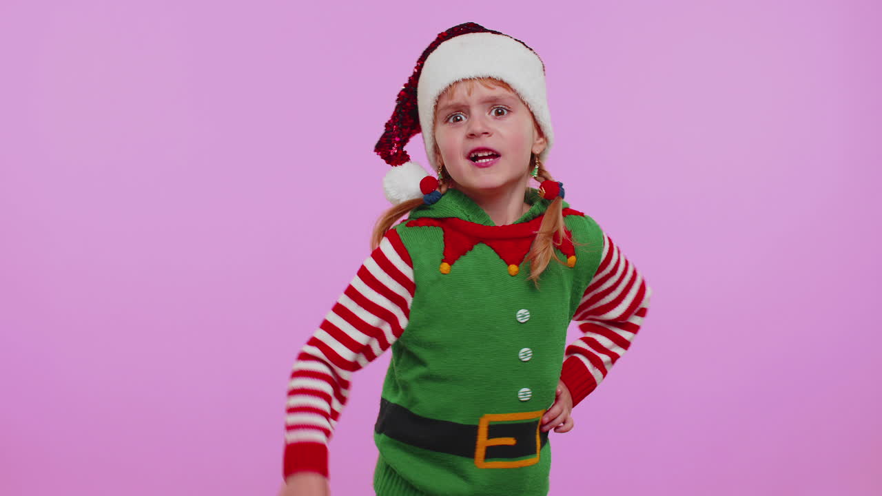 Nespokojená dívka ve vánočním kostýmu nespokojeně gestikuluje rukama, obviňuje a kárá za neúspěch.