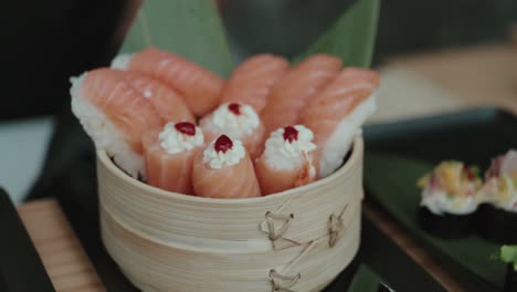 sushi with salmon slices and cream topping served in bamboo bowl with elegant presentation