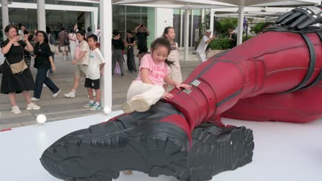 children climb an 8-meter marvel deadpool installation as locals and tourists take photos. the display promotes disney's movie "deadpool and wolverine" in hong kong.