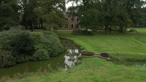 Niedrige-Antenne-über-Schönem-Schlossgarten-Mit-Einem-Großen-Herrenhaus-Im-Hintergrund