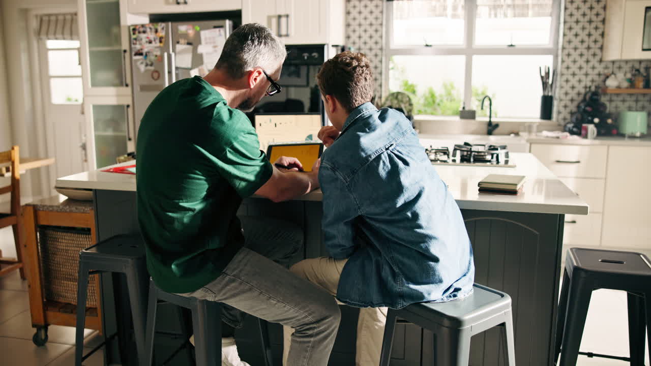Father and son using laptop in kitchen
