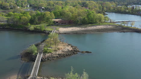 an aerial view over a quiet pond which is surrounded by green trees on a sunny day