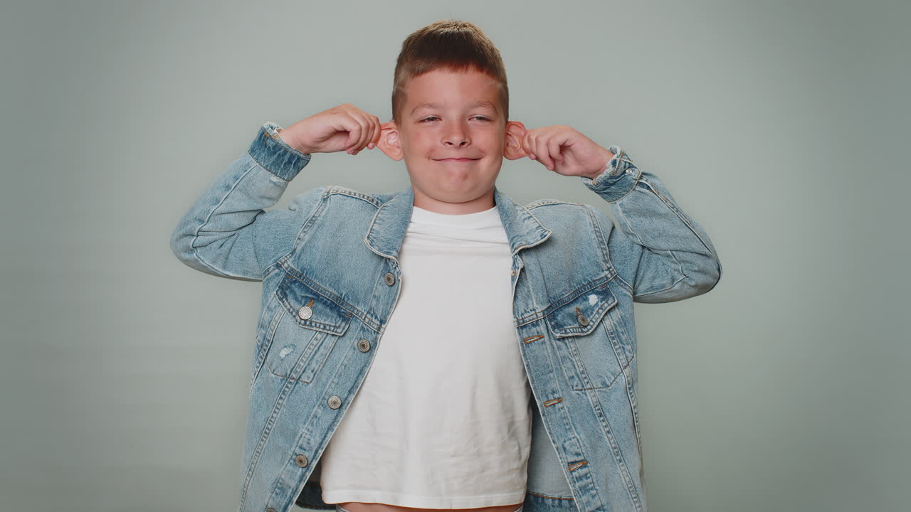 재미있는 유아 소년은 장난스러운 어리석은 얼굴 표정을 하고, 미소 짓고, 혀를 보여주고 놀고 있습니다.