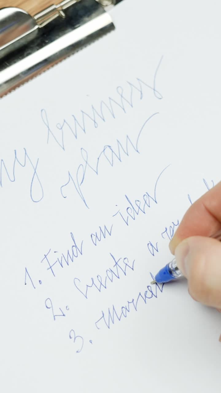 handwriting first steps of a business plan on white paper secured to clipboard, initial plan, foundational stages of business development