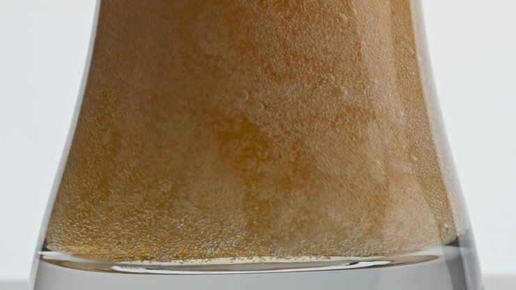 Pasteurized lager beer bubbling vessel closeup. Barley beverage inside goblet