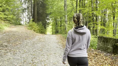 back view of a woman walking through the forest in bucegi mountains, romania