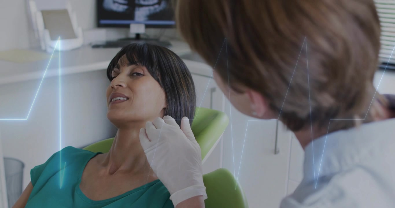 Clinico che posiziona la mano guantata palpando la mascella durante un esame dentale, con sovrapposizione di ECG che traccia la risposta del paziente.