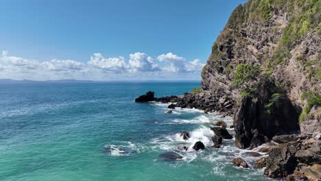 Low-angle-drone-shot-around-the-rocks-as-the-tide-hits-them