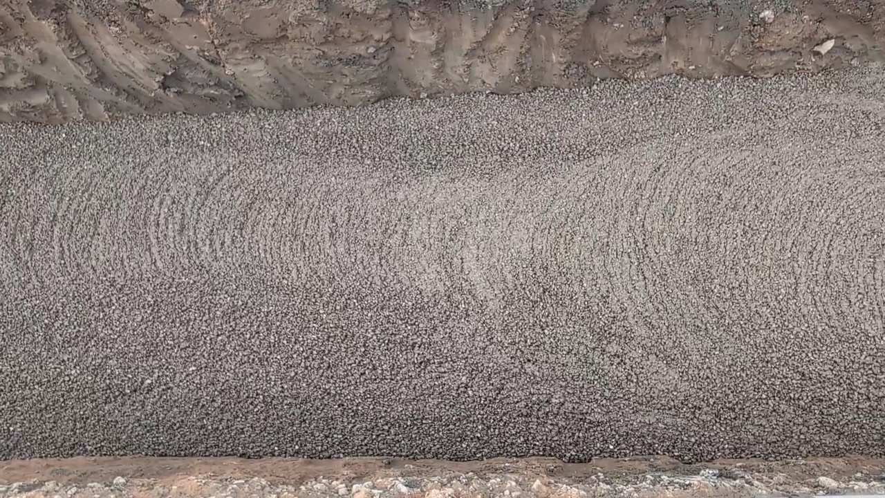 Concrete flows smoothly into a prepared trench, forming intricate patterns. Ideal for construction industry visuals or educational content on building processes.