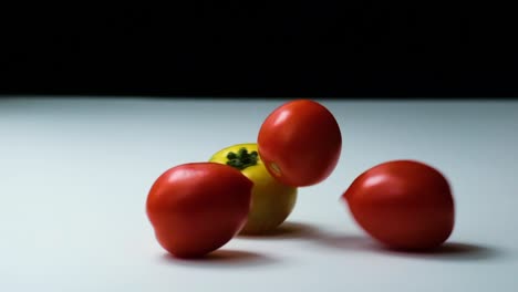 Diferentes-Tipos-De-Tomates-Cayendo-Sobre-La-Superficie,-Vista-De-Estudio