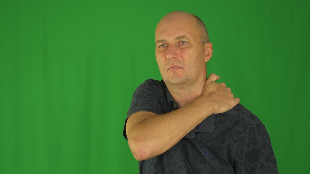 hombre frotando los hombros con la mano izquierda. vista delantera de la cintura en camisa polo.