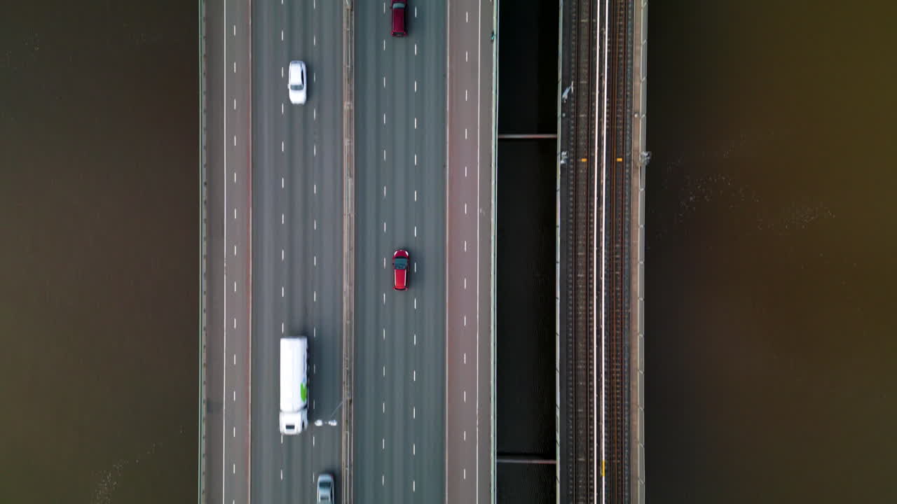 철도 트랙 의 갈색 물 위의 다리를 따라 운전하는 빨간 차의 상단