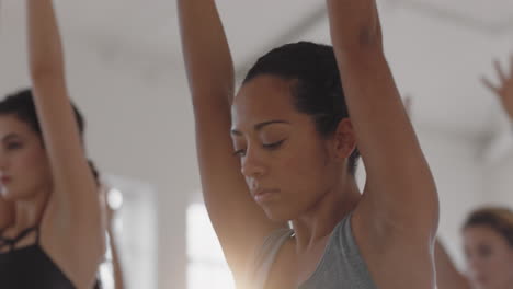 hermosa mujer de yoga de raza mixta practicando meditación de pose guerrera con un grupo de mujeres multirraciales disfrutando de un estilo de vida saludable haciendo ejercicio en un gimnasio al amanecer.