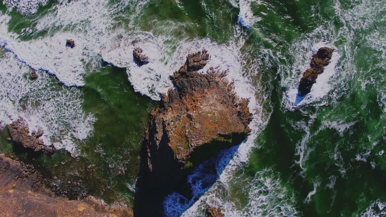 aéreo descendiendo sobre la roca del océano, rompiendo patrones de olas, texturas
