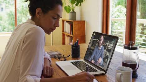 Afroamerikanische-Frau-Macht-Sich-Notizen,-Während-Sie-Zu-Hause-Einen-Videoanruf-Auf-Dem-Laptop-Führt