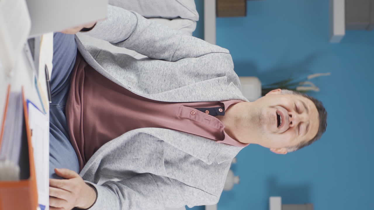 вертикальное видео домашнего офисного работника старик чувствует себя физически хорошо.