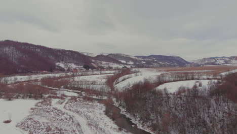 Aerial-view-of-a-river-and-the-mountains-on-a-winter-day-in-Romania