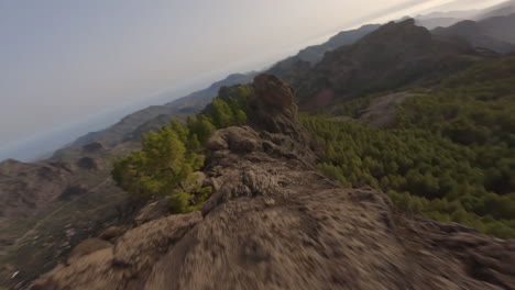 FPV-fast-aerial-view-following-Roque-Nublo-extreme-woodland-rocky-mountain-ridge-Gran-Canaria