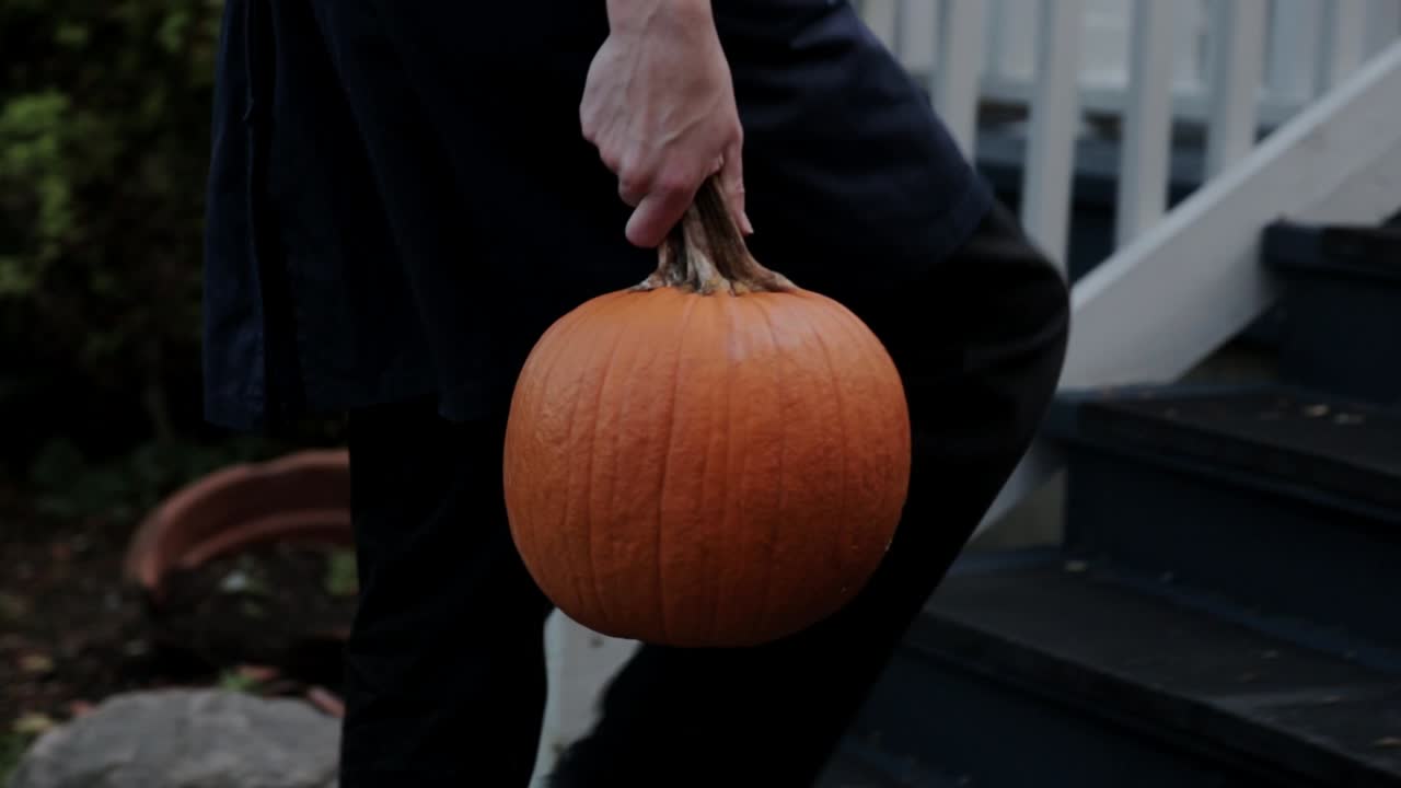 A Person With Pumpkin Walking Towards His House - Close Up Shot
