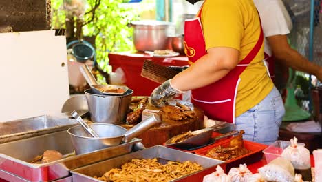 vendor prepares roasted chicken at bangkok market