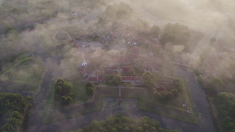 Toma-Aérea-De-La-Famosa-Fortaleza-Bourtange-Cubierta-Con-Una-Pequeña-Capa-De-Niebla-Durante-El-Amanecer,-Antena