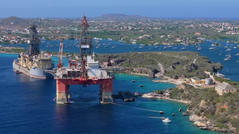 high-altitude aerial orbit of oil platform near the coast, surrounded by clear blue waters and scenic views