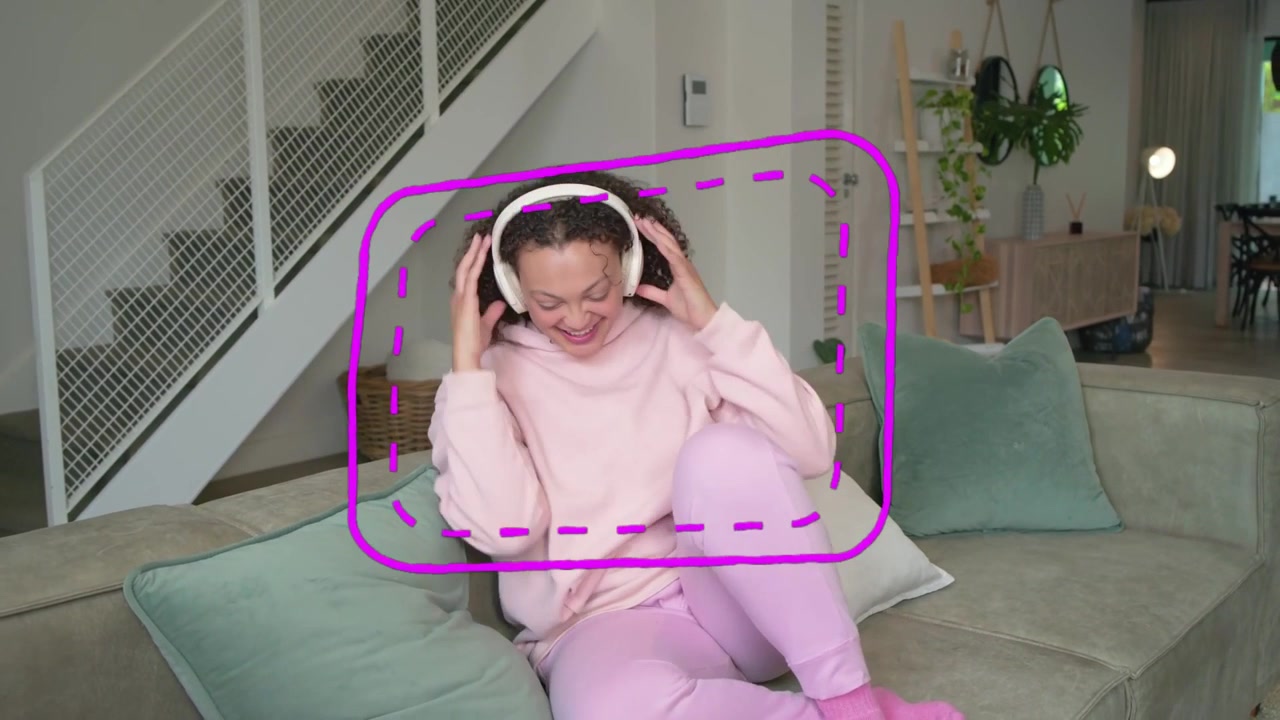 Donna sul divano che indossa le cuffie, toccando il telefono mentre appare una sovrapposizione magenta, ascoltando musica.