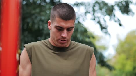 Young-athletic-man-doing-push-ups-at-red-sports-facility-in-park