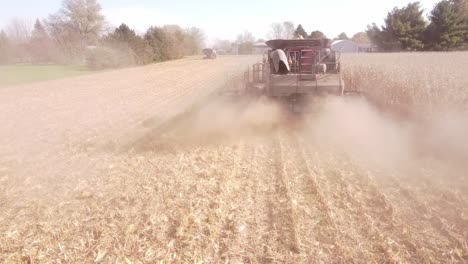 Combine-Harvester-Harvesting-Corn-Emits-Clouds-Of-Dust-and-Smoke,-in-Southeast-Michigan---drone-shot