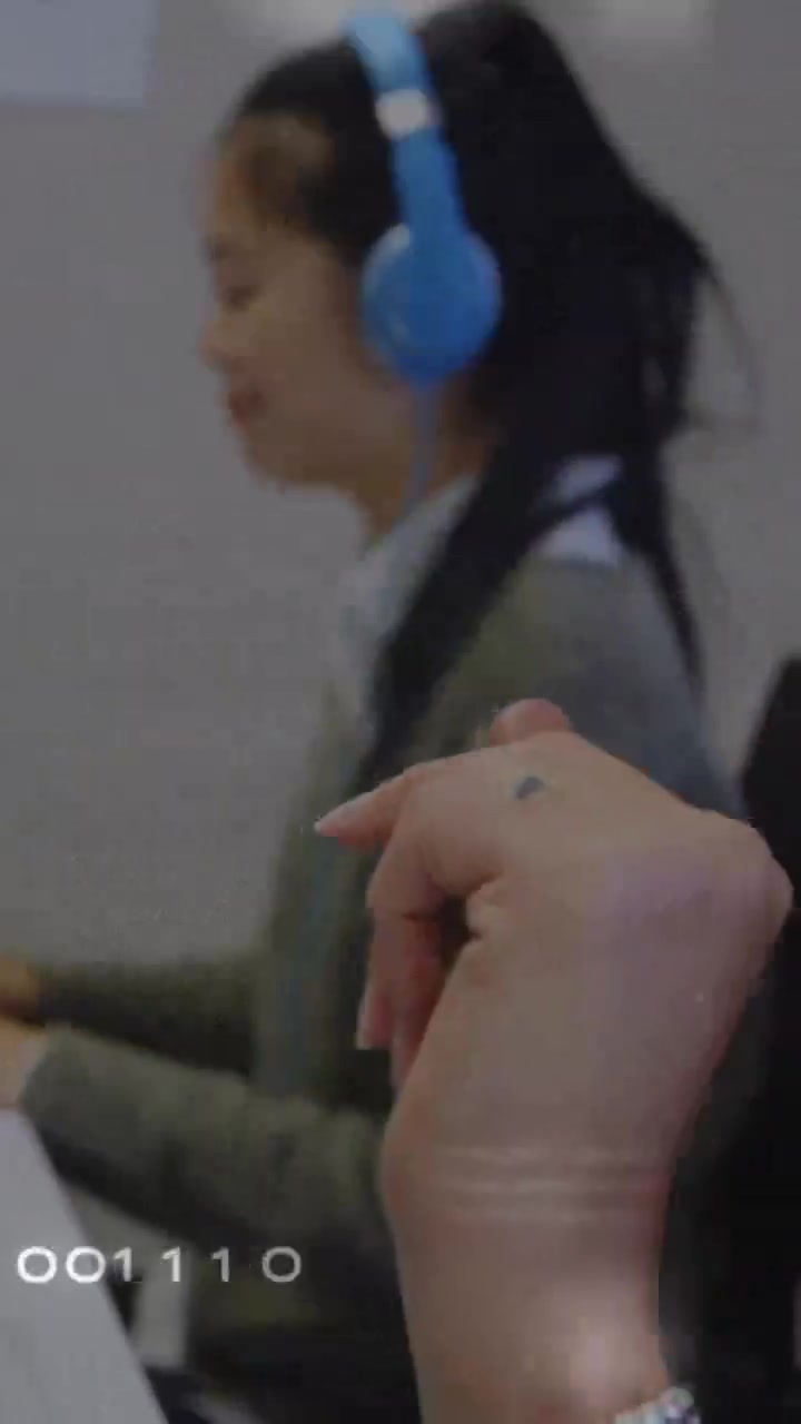 Video verticale: Donna con cuffie blu in audio, che digita e parla per uno studio, con indicazione oraria visibile.