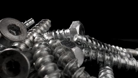 close-up of a pile of metal screws on a black background