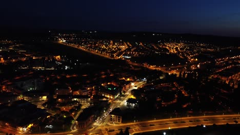 nocturnal aerial view of a small city illuminated by orange city lights, establishing shot