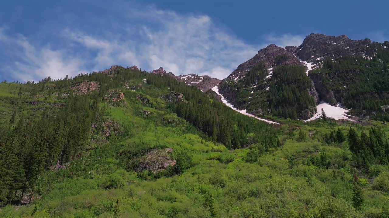 Pyramid Peak looking up from Maroon Creek Lake Aspen Snowmass Maroon Bells Wilderness spring summertime sunny morning blue sky aerial drone Colorado Rocky Mountains Elk Range Mountains pan right
