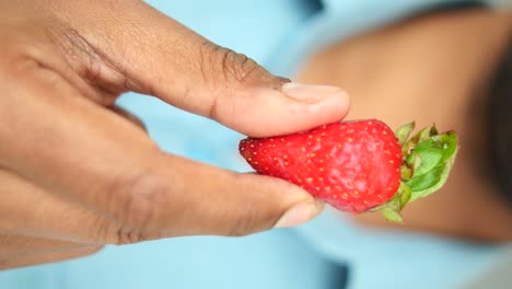 hand holding a single strawberry