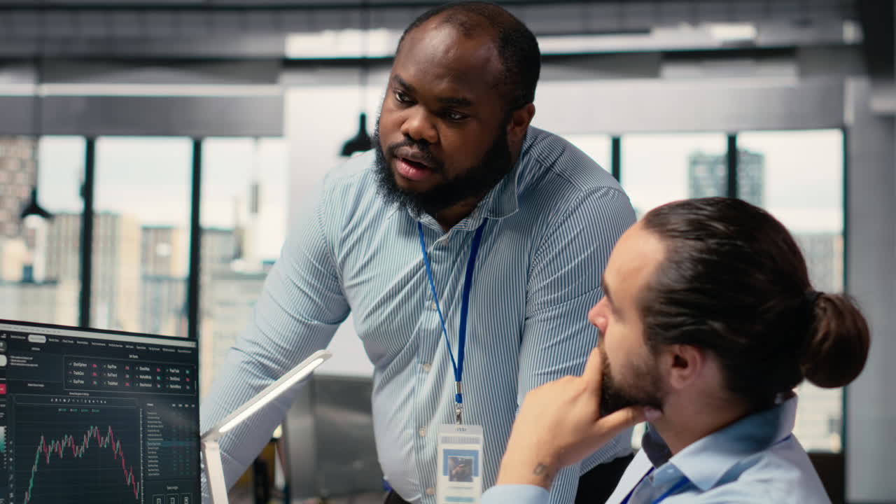 Coworkers collaborate on trading strategies in office, review stock market data