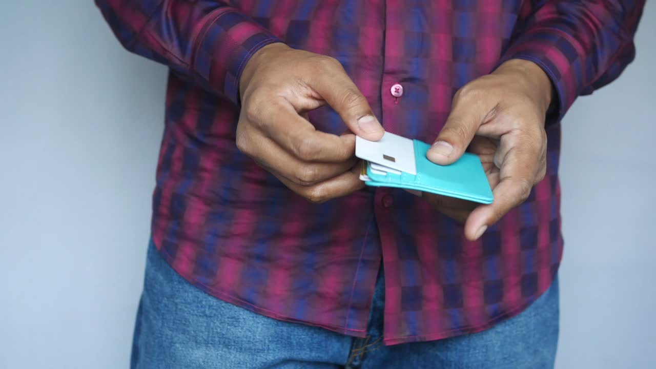 persona que abre una billetera azul azul con una tarjeta de crédito
