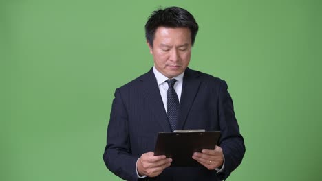 mature japanese businessman against green background