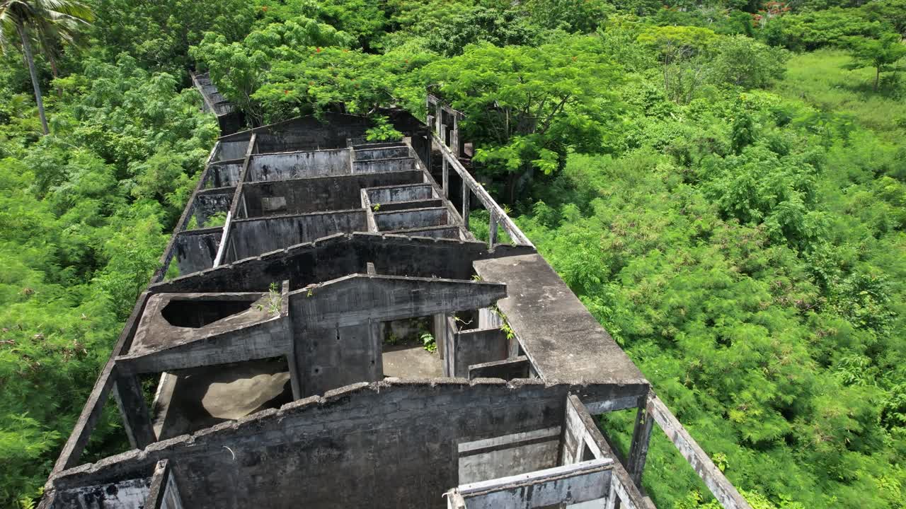 Abandoned Concrete Building Hotel surrounded by green lush tropical forest- aerial fly over