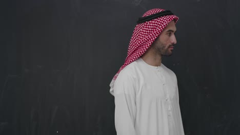 portrait of young arabian man in traditional clothes in front of black chalkboard