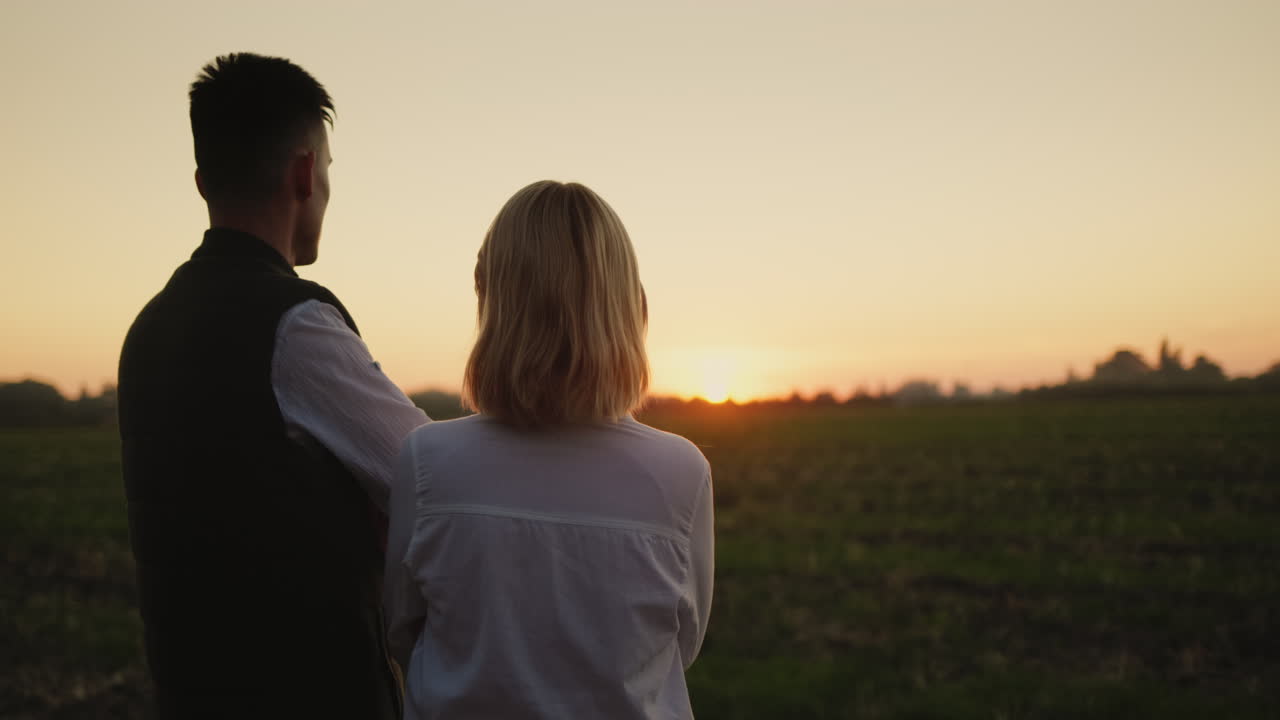 몇 명의 농부 들 이 자기 들 의  ⁇  을 바라보고 있다. 태양 이 지평선 위 에 지고 있다