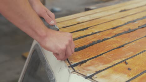 Trimming-mastic-flashing-excess-on-cabin-roof-planking-of-wooden-boat