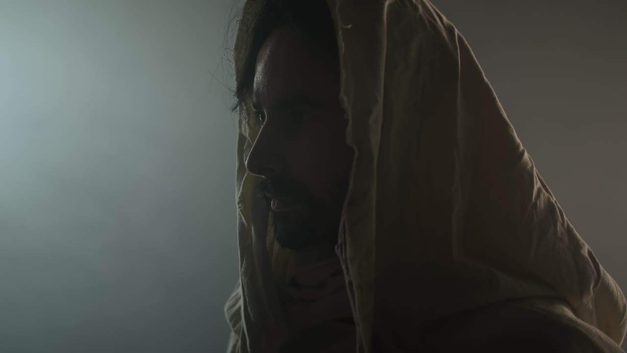 Jesus Christ resurrected on Easter Sunday inside empty tomb in bright, shining light, wearing white hood and robe. Cinematic Christian visual.