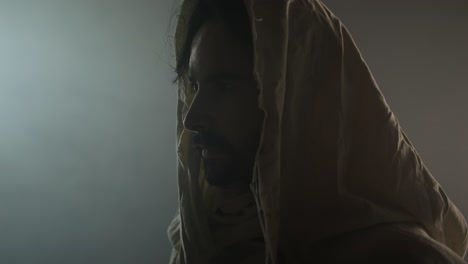 jesus christ resurrected on easter sunday inside empty tomb in bright, shining light, wearing white hood and robe. cinematic christian visual.