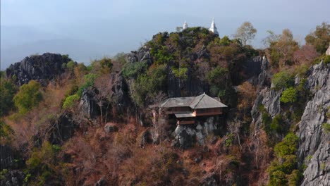 Drone-aerial-view-of-buddhist-Thai-house-temple-in-the-sky-on-top-rocky-mountains