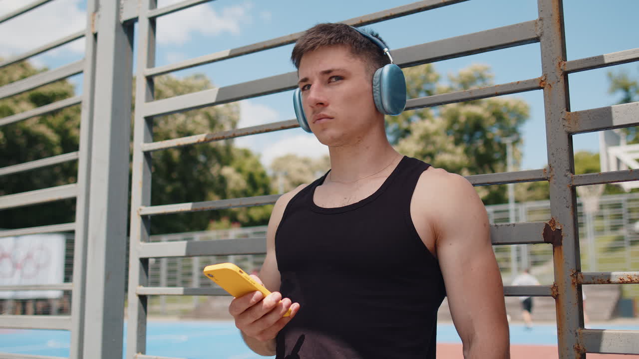 Athletic caucasian man in sportswear enjoying listening to music in earphones from smartphone app