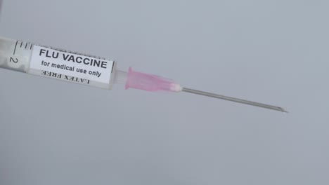 hand with syringe to administer flu vaccine - close up